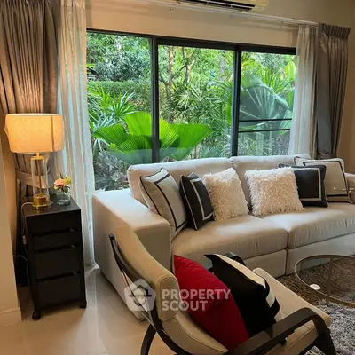 Stylish living room with cozy sofa and lush garden view through large windows.