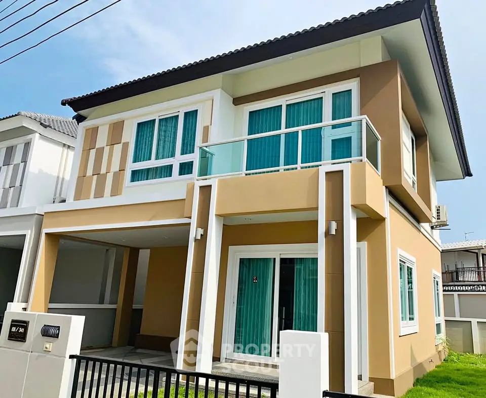 Modern two-story house with large windows and balcony in a suburban neighborhood.