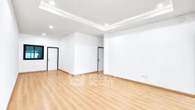 Spacious empty room with wooden flooring and recessed lighting, ideal for customization.