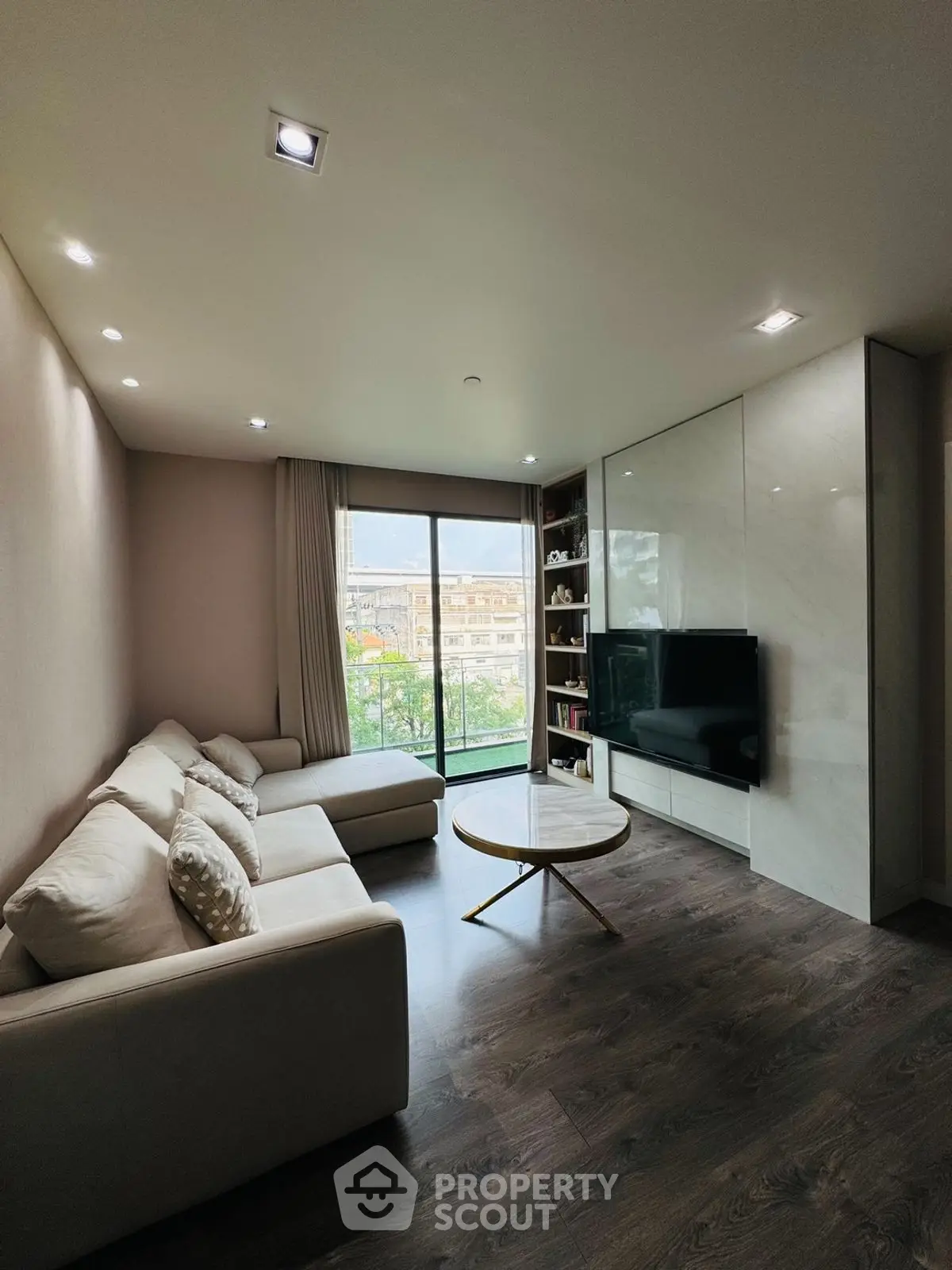 Modern living room with large sofa and TV, featuring a bright window view.