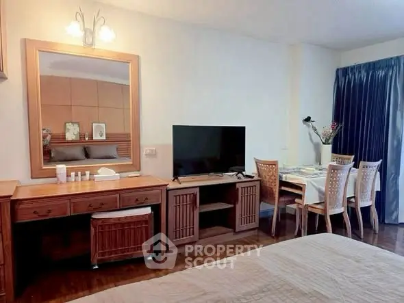 Cozy bedroom with TV and dining area, featuring wooden furniture and elegant decor.