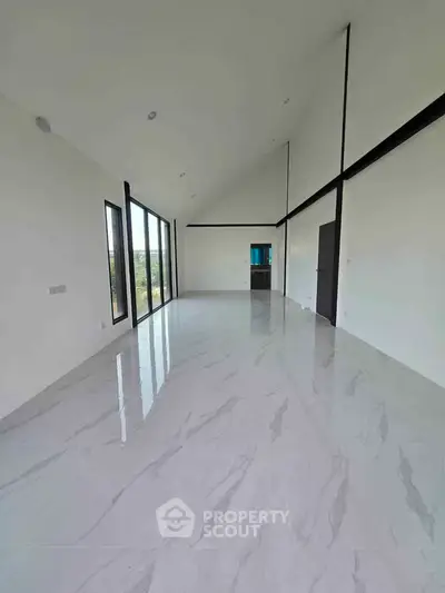 Spacious modern living room with high ceilings and large windows offering natural light and scenic views.