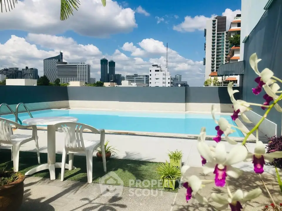 Stunning rooftop pool with city skyline views and vibrant flowers.