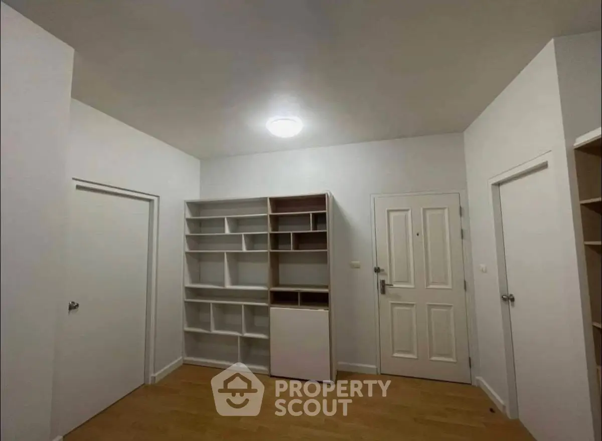 Spacious room with built-in shelving and wooden flooring, ideal for versatile use in modern home.