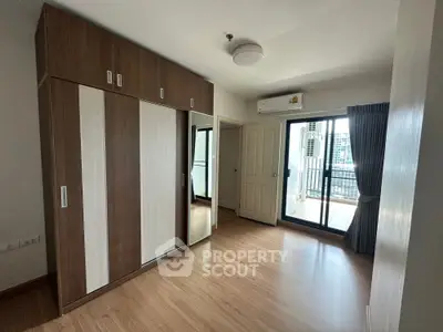 Modern bedroom with balcony access and wooden wardrobe in urban apartment.