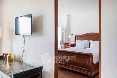 Elegant bedroom with wooden bed frame and wall-mounted TV, perfect for relaxation.