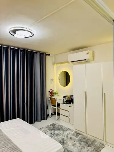 Modern bedroom with sleek furniture and ambient lighting, featuring a stylish vanity and air conditioning.