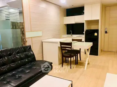 Modern living room with sleek furniture and compact kitchen in open layout apartment.