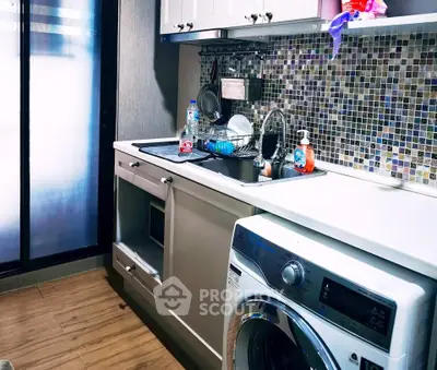 Modern kitchen with washing machine and mosaic backsplash in cozy apartment.