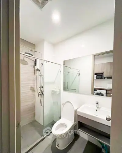 Modern bathroom with glass shower and sleek fixtures in contemporary apartment.