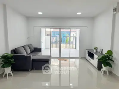Spacious modern living room with sleek sofa and large sliding glass doors opening to patio.