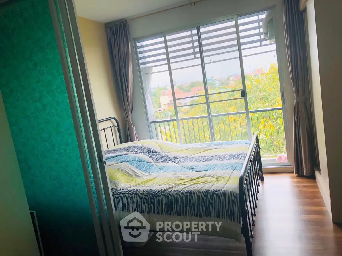 Bright bedroom with large window and balcony view, featuring a cozy bed and stylish curtains.