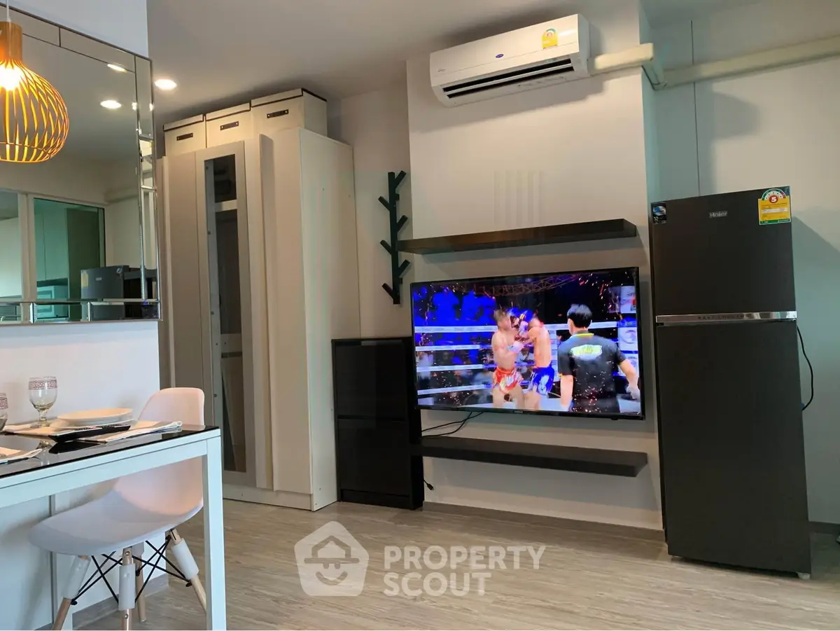 Modern living room with air conditioning, TV, and dining area in stylish apartment.