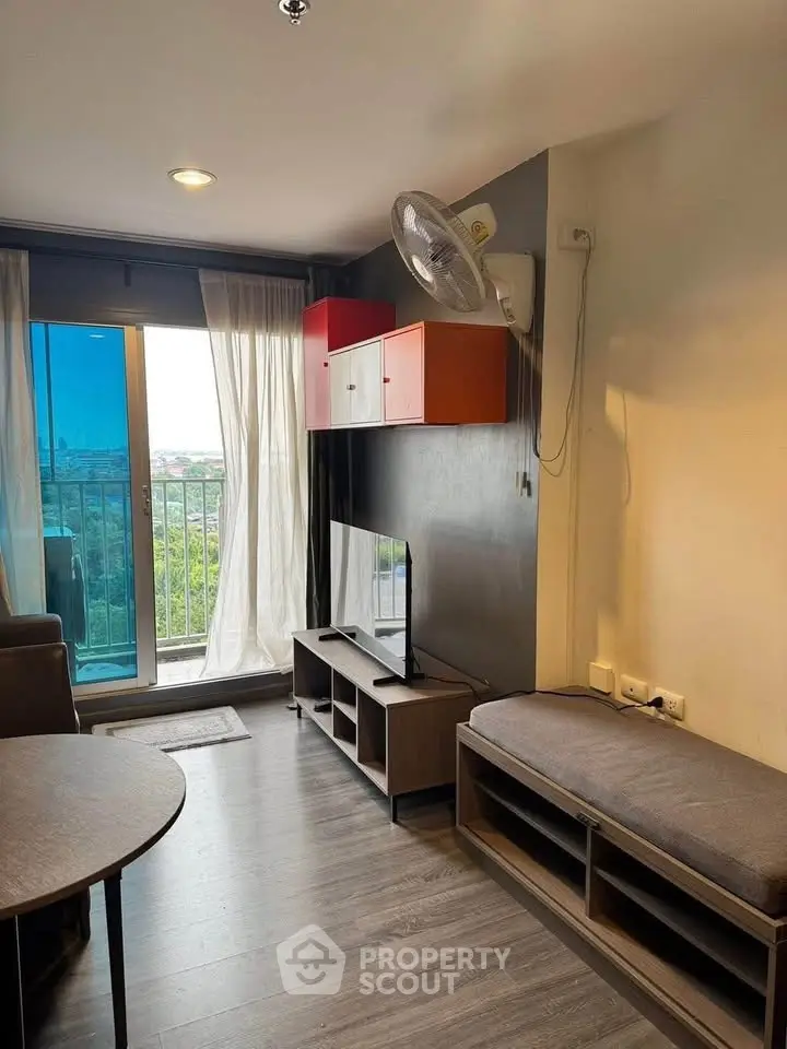 Modern living room with balcony view, stylish furniture, and natural light.