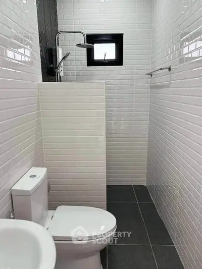 Modern minimalist bathroom with sleek white tiles and compact design.