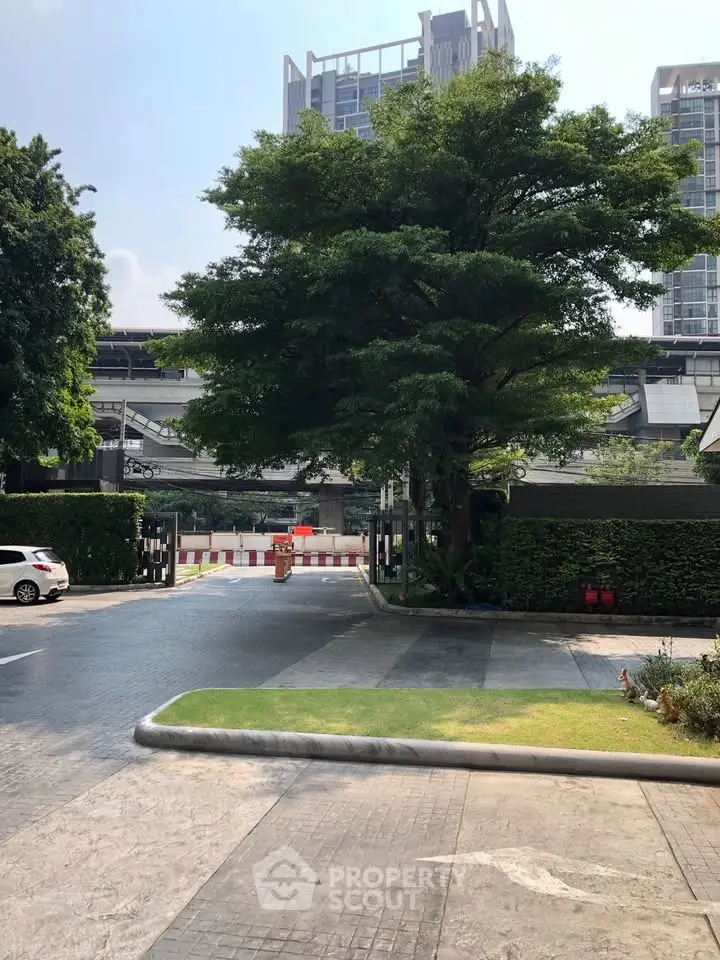 Modern urban building exterior with lush greenery and driveway entrance.