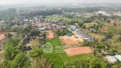 Aerial view of a residential area with lush greenery and developing plots.