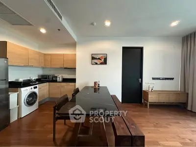 Modern kitchen with sleek black dining table, wooden cabinets, and built-in appliances.