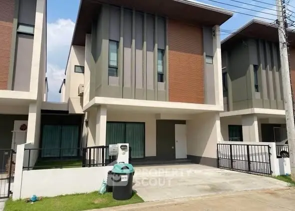 Modern two-story townhouse with sleek facade and driveway in suburban neighborhood.