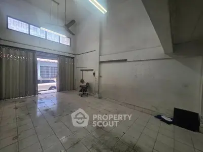 Spacious empty room with high ceiling and tiled floor, ideal for commercial use or storage.