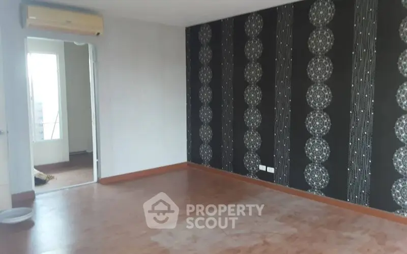 Spacious empty room with unique patterned wallpaper and wooden flooring, ideal for customization.