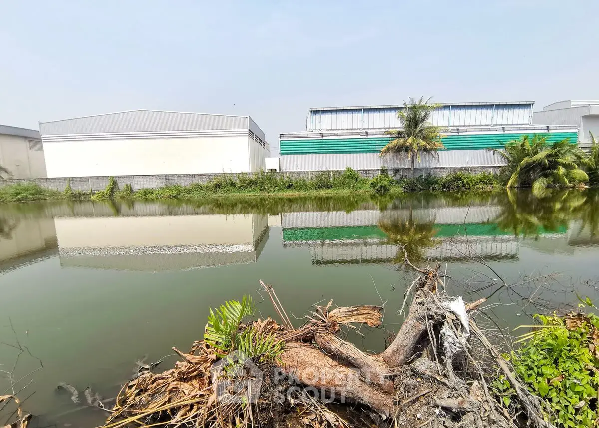 Industrial buildings reflected in a tranquil pond, showcasing serene surroundings and potential for commercial use.