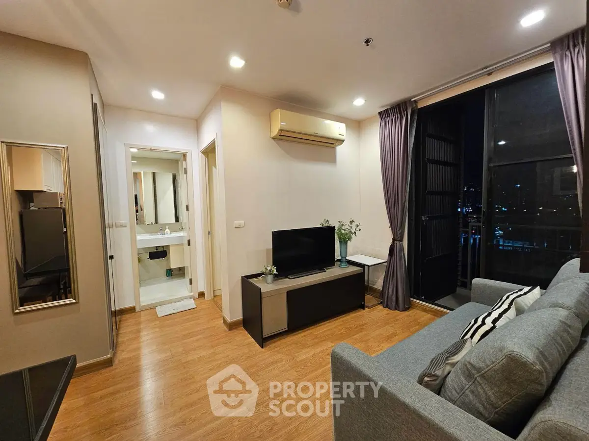 Modern living room with cozy sofa, TV, and city view balcony in stylish apartment.