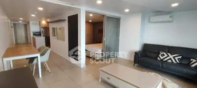Modern open-plan living room with dining area and sliding door to bedroom, featuring sleek furniture and bright lighting.