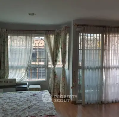 Cozy bedroom with large windows and floral curtains in a bright apartment