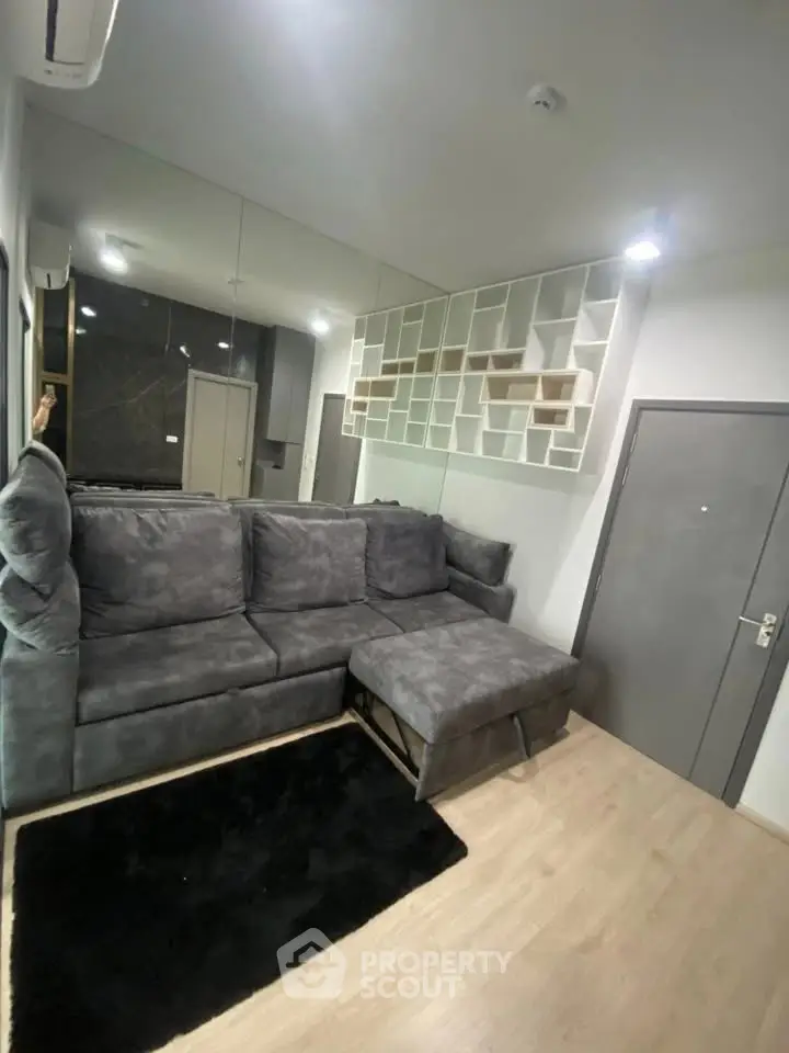 Modern living room with plush gray sectional sofa and stylish shelving, perfect for cozy relaxation.