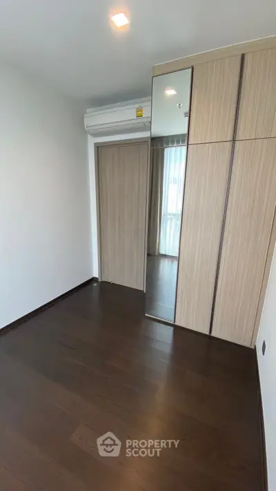 Spacious bedroom with wooden flooring and built-in wardrobe, ideal for modern living.