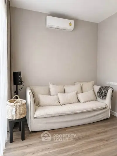 Modern living room with cozy beige sofa and air conditioning, perfect for relaxation.
