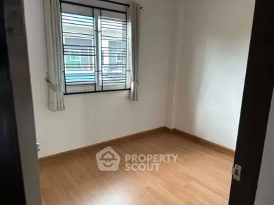 Spacious empty room with wooden flooring and large window, perfect for customization.