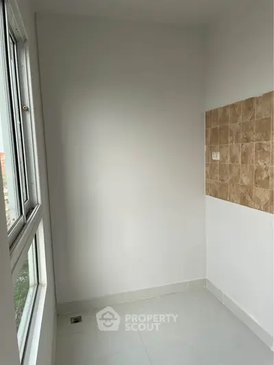Bright utility room with tiled wall and large window, perfect for laundry or storage.