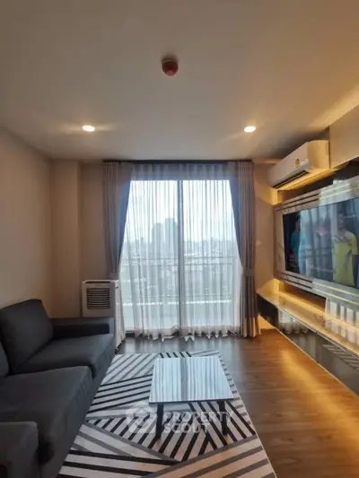 Modern living room with large window and stylish decor in a high-rise apartment.