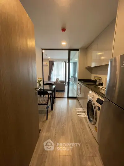 Modern apartment with open kitchen and living area, featuring sleek appliances and stylish decor.
