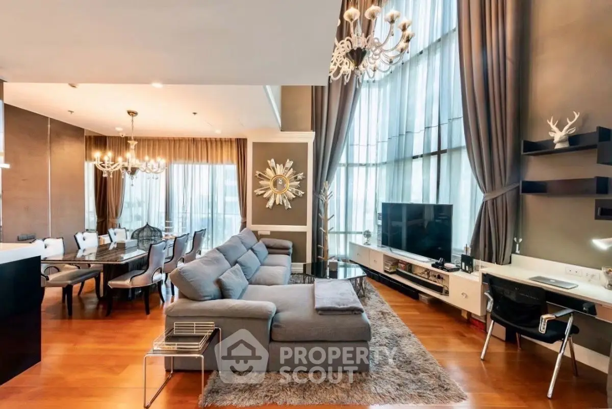 Luxurious living room with high ceilings, elegant chandeliers, and modern furnishings in a spacious open layout.