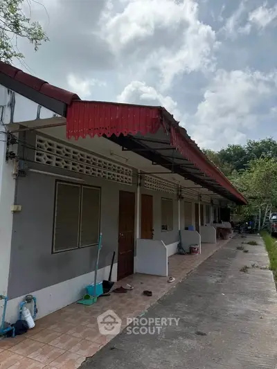 Charming single-story building with red roof and outdoor walkway, perfect for residential or commercial use.