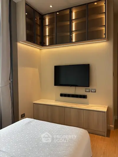 Modern bedroom with sleek TV setup and elegant lighting