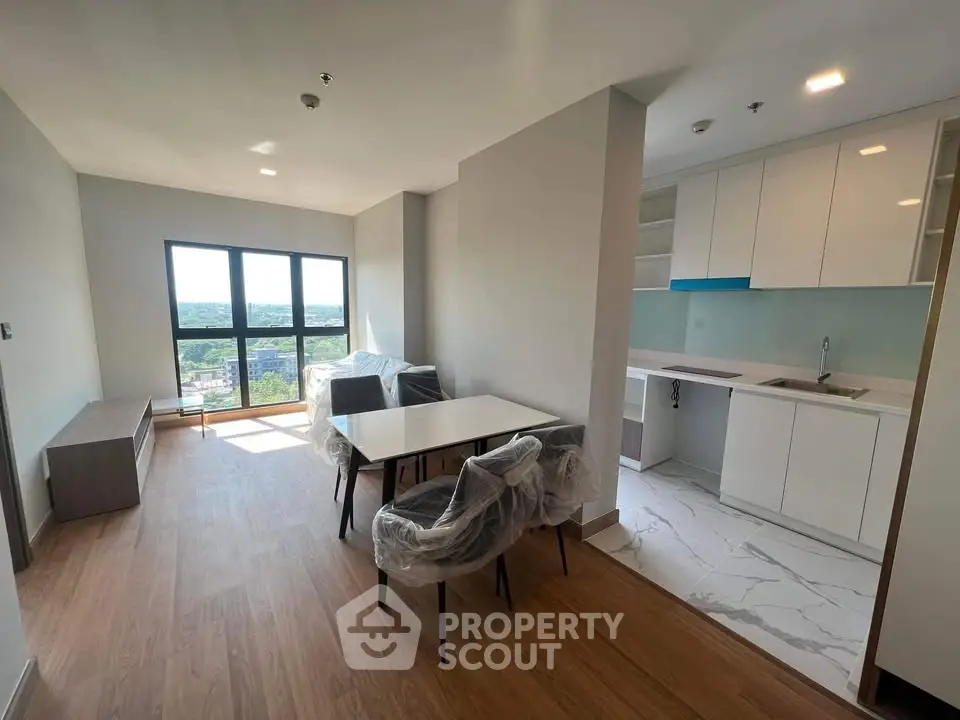 Modern open-plan living room and kitchen with large windows and stylish furnishings.