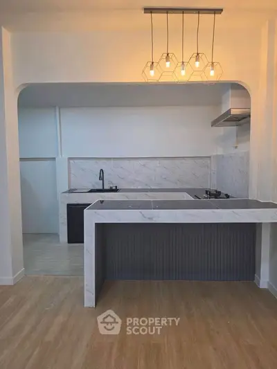 Modern kitchen with marble countertops and stylish lighting in open layout design.