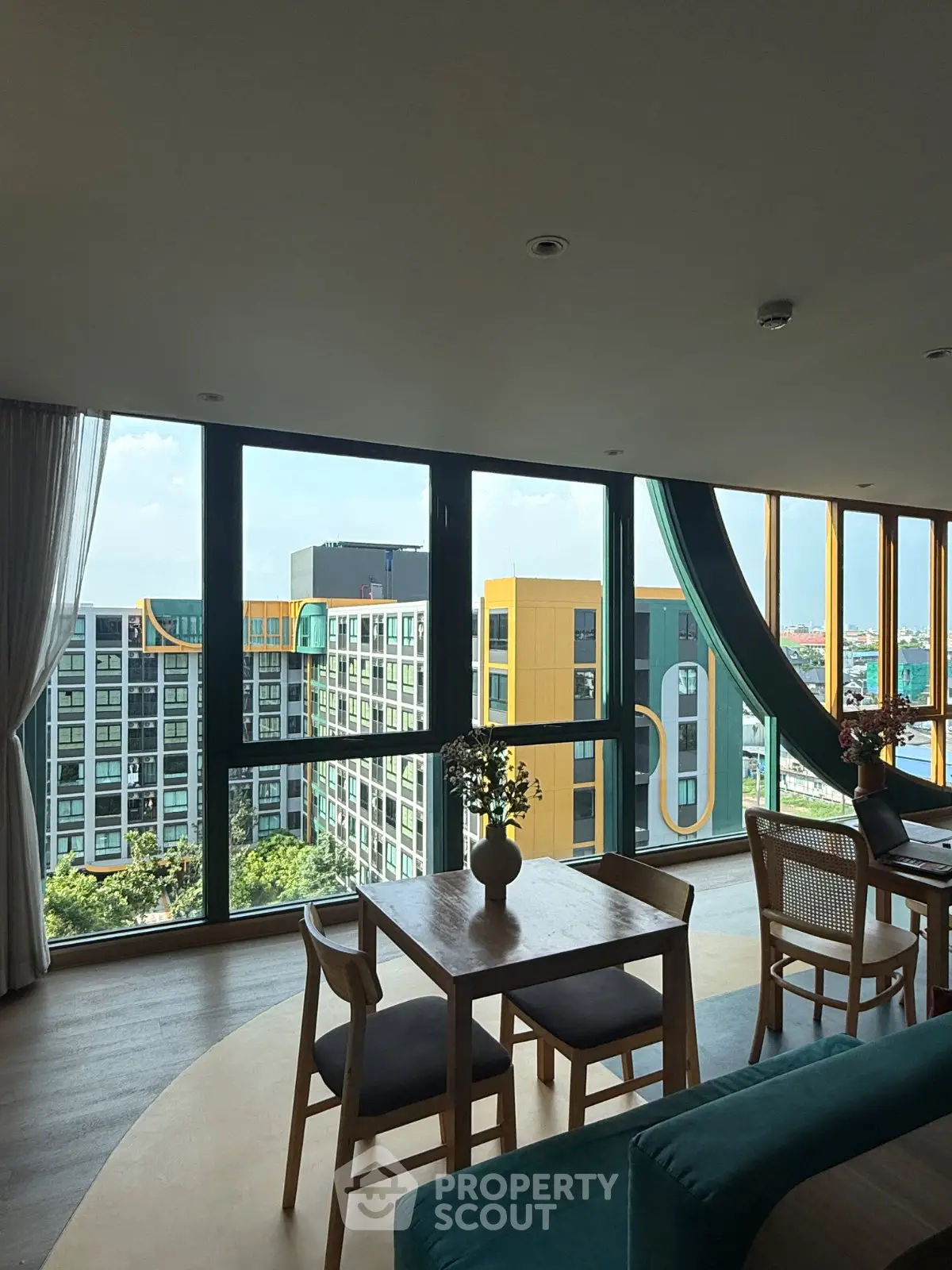 Modern living room with large windows offering stunning city views and stylish furniture.