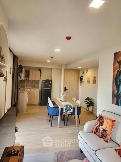 Modern open-plan living room with stylish kitchen and dining area, featuring contemporary decor and natural light.