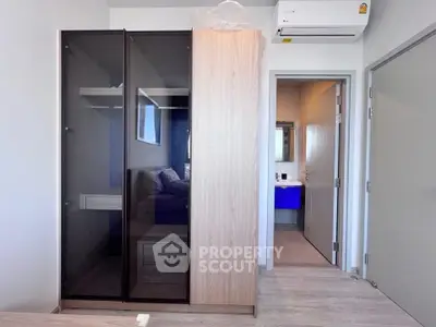 Modern bedroom with sleek wardrobe and ensuite bathroom in a stylish apartment.