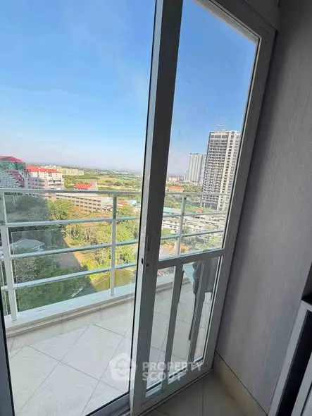 Stunning balcony view from high-rise apartment overlooking cityscape and greenery.