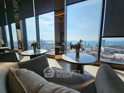 Luxurious high-rise living room with panoramic city and ocean views, featuring elegant decor and plush seating.