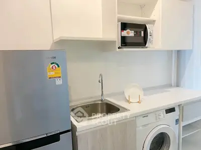 Modern kitchen with sleek appliances including fridge, microwave, and washing machine.