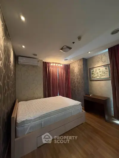 Spacious bedroom with elegant wallpaper and natural light, featuring a comfortable bed and stylish wooden flooring.