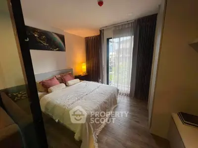 Cozy bedroom with elegant decor and natural light from large window, perfect for relaxation.