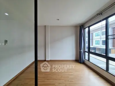 Spacious empty room with large windows and wooden flooring, perfect for customization.